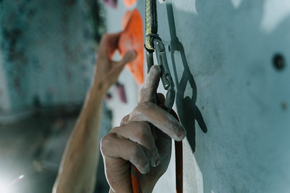 Detailed shot of hands using a carabiner while rock climbing indoors, conveying action and focus.